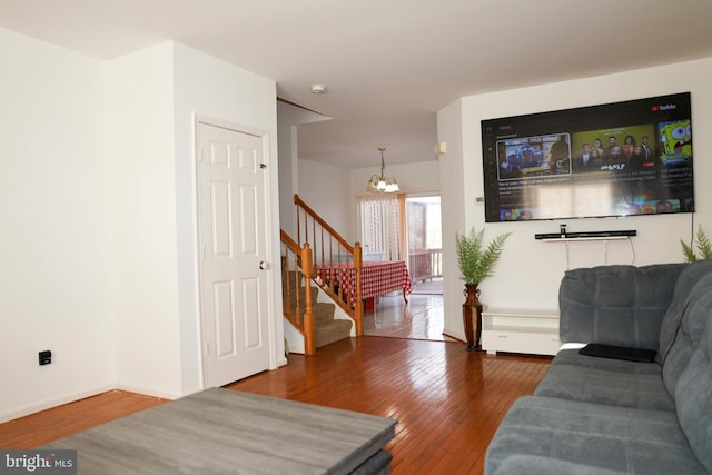 living area with a notable chandelier, stairway, baseboards, and wood-type flooring