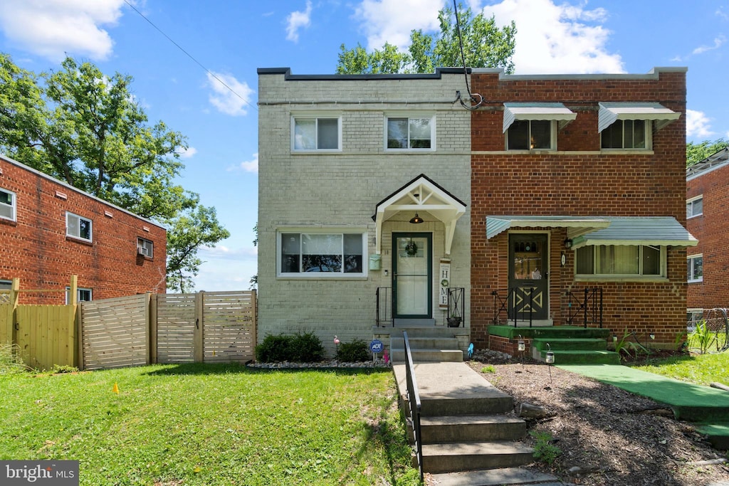 view of front of property featuring brick siding, a front lawn, and fence