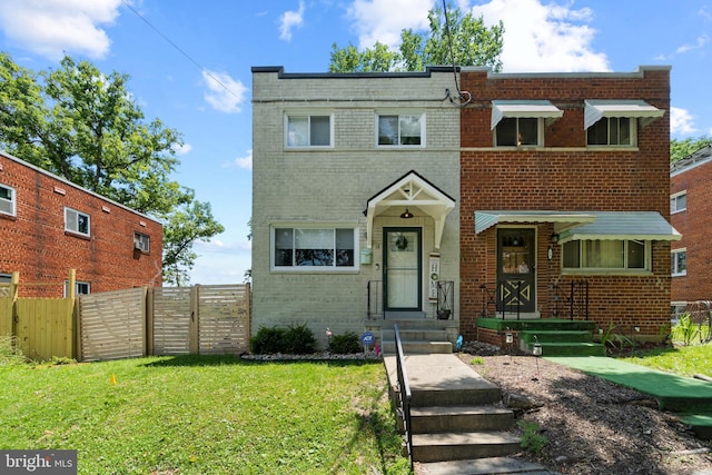 view of front of property featuring brick siding, a front lawn, and fence