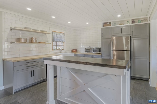 kitchen featuring decorative backsplash, open shelves, gray cabinets, and wood counters