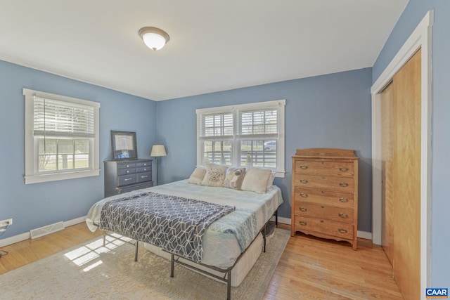 bedroom with multiple windows, baseboards, and wood finished floors