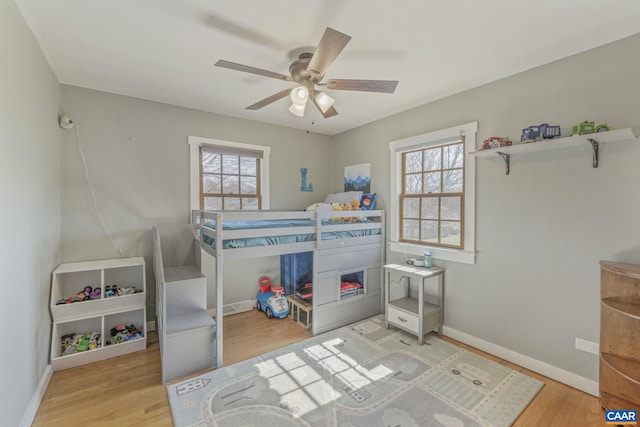 bedroom with ceiling fan, baseboards, and wood finished floors