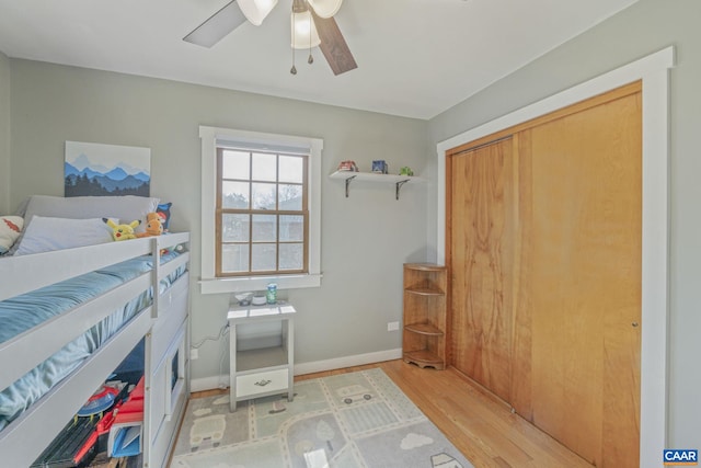 bedroom with light wood-type flooring, baseboards, and a ceiling fan