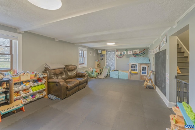 game room with beam ceiling, a wealth of natural light, and a textured ceiling