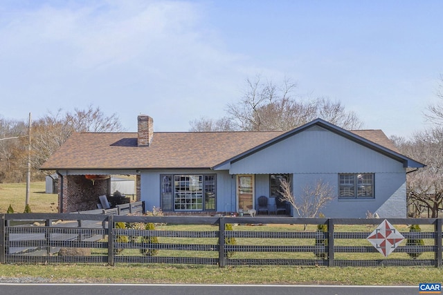 view of front of home featuring a fenced front yard, brick siding, a chimney, and a shingled roof