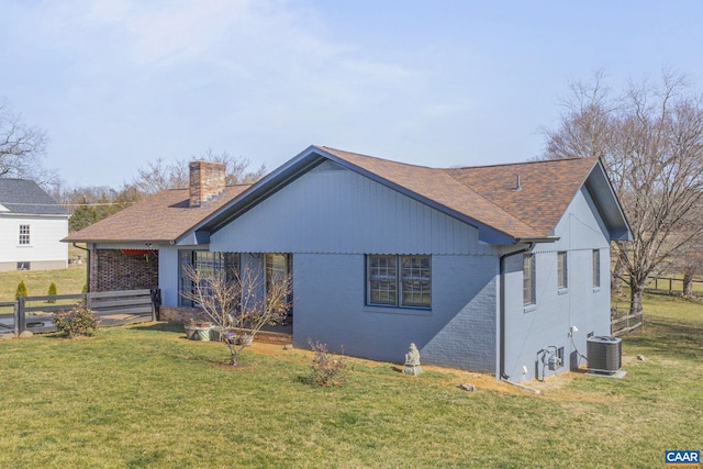 exterior space with brick siding, fence, a front yard, cooling unit, and a chimney