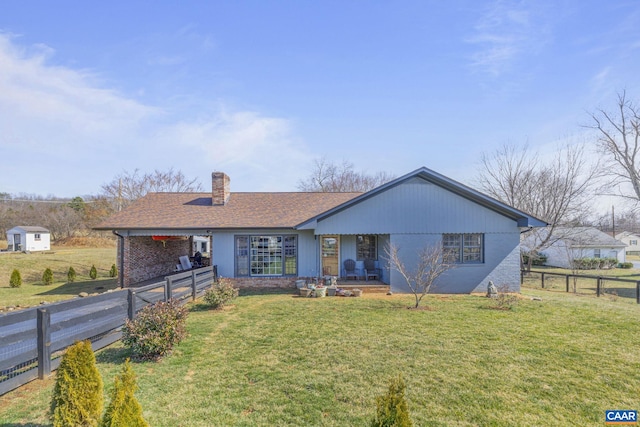 view of front of house featuring brick siding, a chimney, a front yard, and fence