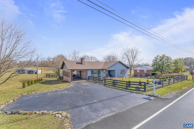 view of front of property with a front yard, a chimney, a fenced front yard, and aphalt driveway