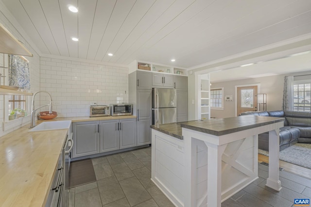 kitchen with appliances with stainless steel finishes, gray cabinets, wooden counters, and a sink