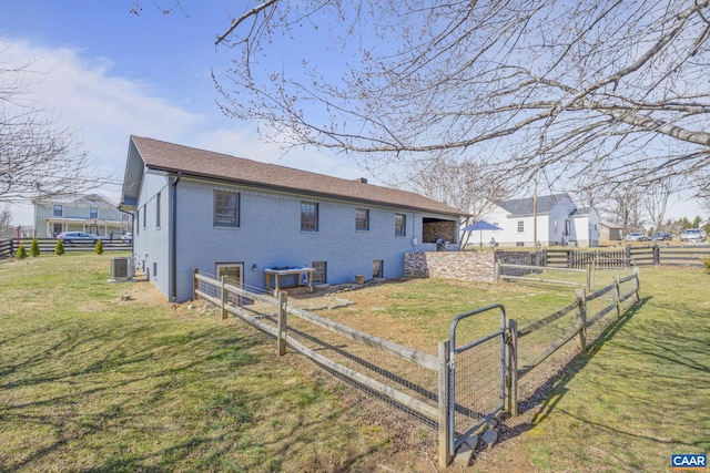 view of side of property with central air condition unit, a gate, fence, a yard, and brick siding