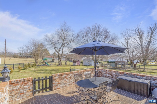 view of patio with a playground, outdoor dining area, and fence