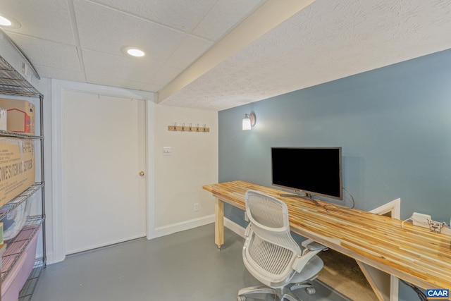 office space featuring baseboards, a drop ceiling, and finished concrete floors