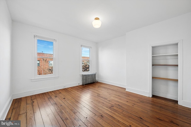 spare room with radiator, baseboards, and wood-type flooring