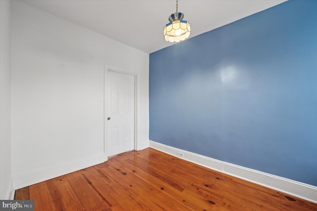 unfurnished room with baseboards and hardwood / wood-style flooring