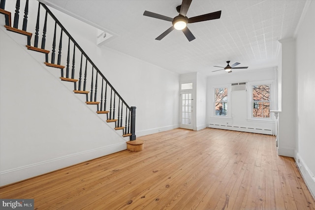 unfurnished living room featuring hardwood / wood-style floors, a ceiling fan, baseboards, a baseboard radiator, and stairs