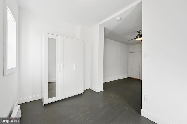 interior space featuring a ceiling fan, dark wood-style floors, a closet, baseboards, and baseboard heating