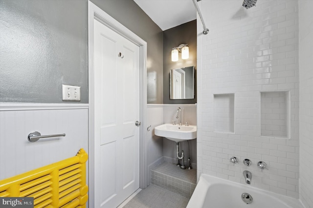 bathroom with a sink, bathtub / shower combination, wainscoting, and tile patterned floors