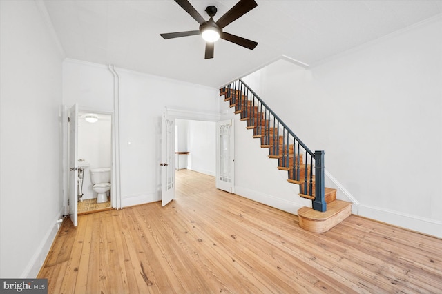 stairs featuring a ceiling fan, hardwood / wood-style flooring, crown molding, and baseboards