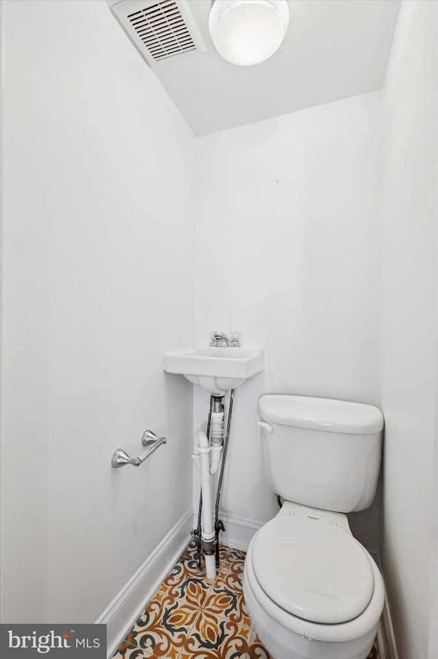 half bathroom featuring tile patterned floors, visible vents, toilet, and baseboards