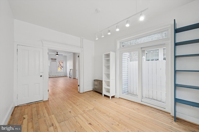 entryway with track lighting, baseboards, radiator heating unit, light wood-style flooring, and a baseboard radiator