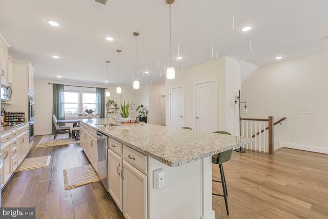 kitchen featuring visible vents, a kitchen bar, light wood-type flooring, stainless steel appliances, and a sink