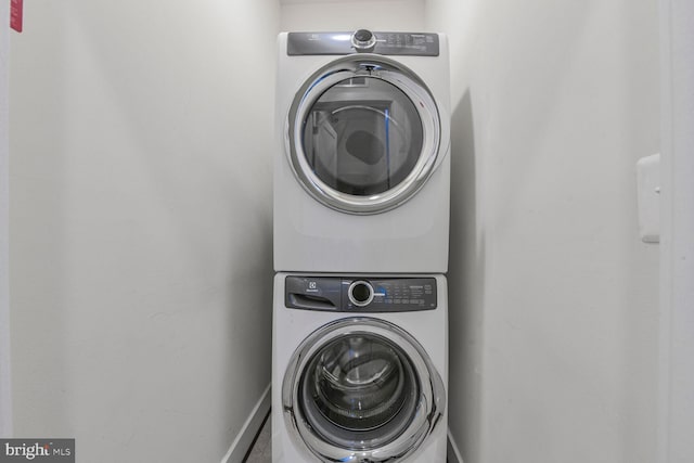 laundry area featuring laundry area, stacked washer and dryer, and baseboards