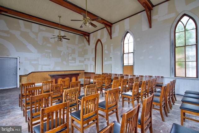 dining space with a wainscoted wall, beamed ceiling, and a towering ceiling