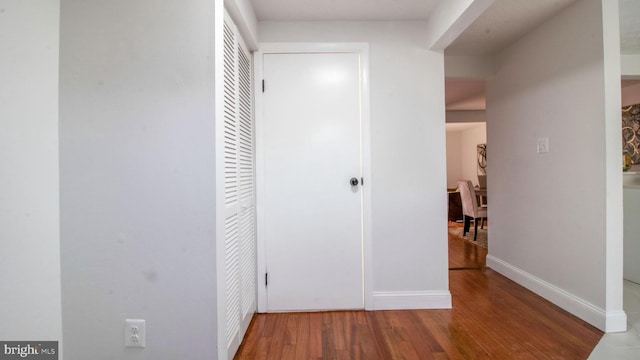 hall with baseboards and wood finished floors