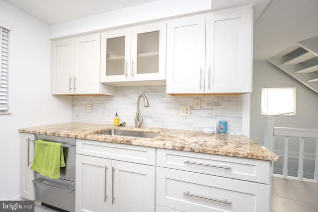 kitchen with decorative backsplash, light stone countertops, and a sink