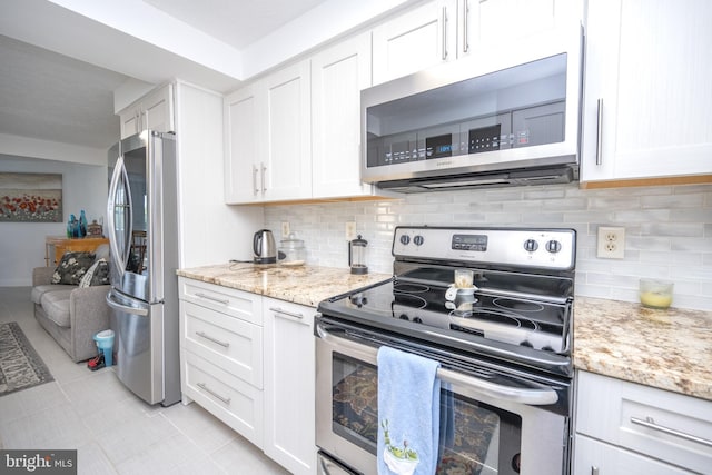 kitchen featuring white cabinetry, light stone countertops, backsplash, and stainless steel appliances