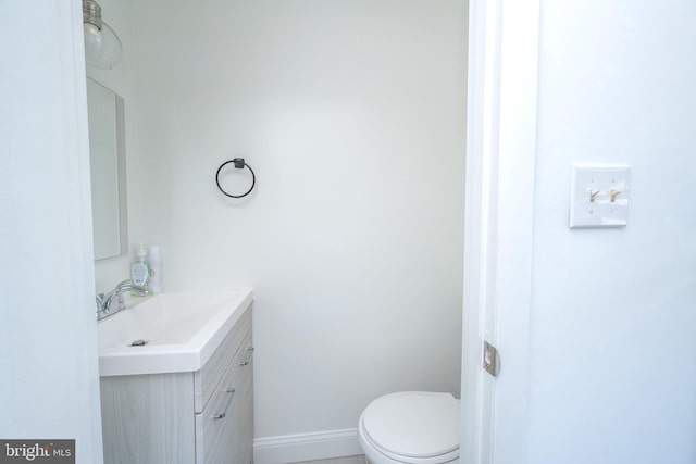 bathroom with toilet, vanity, and baseboards