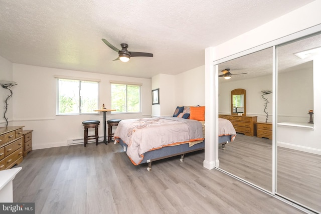 bedroom featuring a baseboard heating unit, baseboards, ceiling fan, wood finished floors, and a textured ceiling