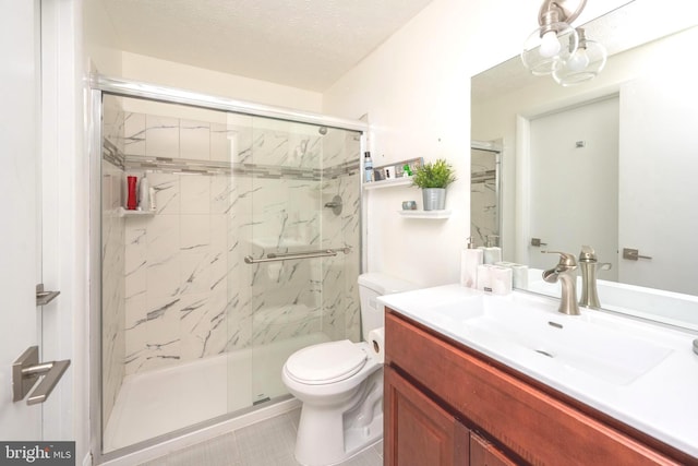 bathroom featuring vanity, a shower stall, toilet, and a textured ceiling