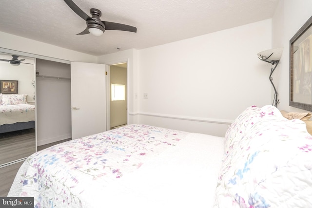 bedroom with ceiling fan, wood finished floors, a closet, and a textured ceiling