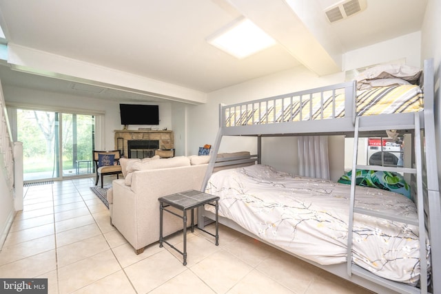 tiled bedroom featuring access to outside, visible vents, beamed ceiling, and a glass covered fireplace