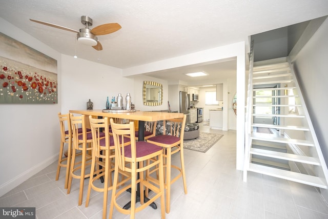 dining space with light floors, a dry bar, a textured ceiling, and baseboards