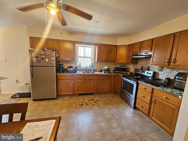 kitchen featuring under cabinet range hood, brown cabinets, stainless steel appliances, and a sink