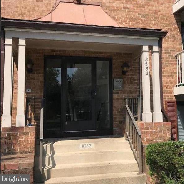 entrance to property featuring brick siding and covered porch