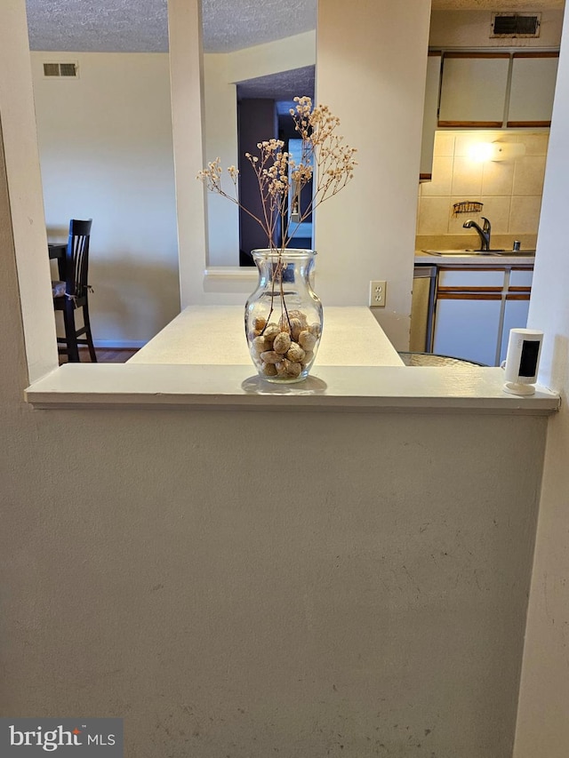 interior space featuring a sink, visible vents, backsplash, and a textured ceiling