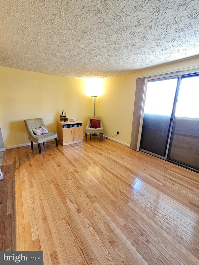 unfurnished room featuring baseboards, a textured ceiling, and light wood finished floors