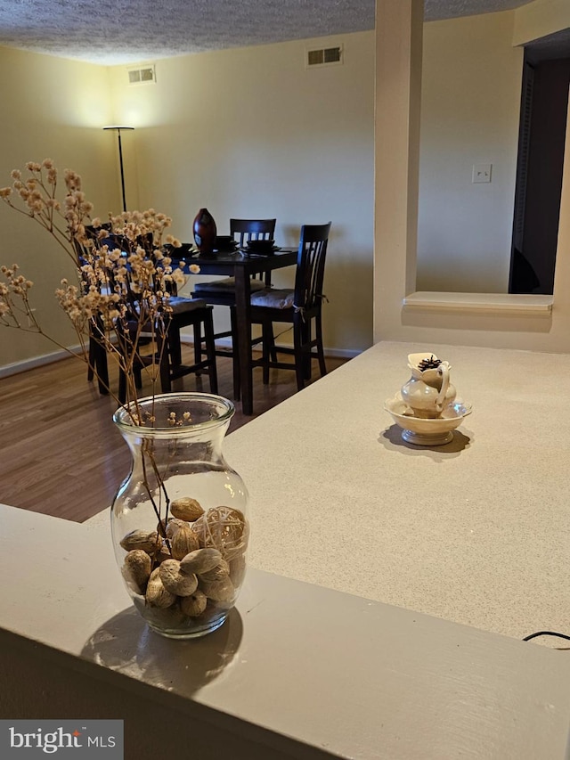 dining room with visible vents, a textured ceiling, and wood finished floors