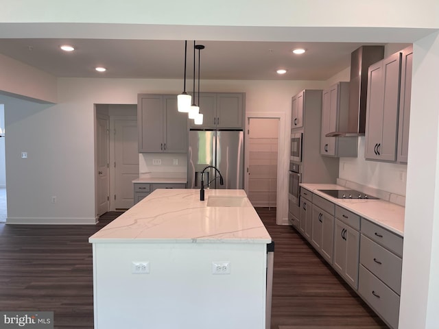 kitchen with dark wood finished floors, gray cabinets, a sink, stainless steel appliances, and wall chimney exhaust hood