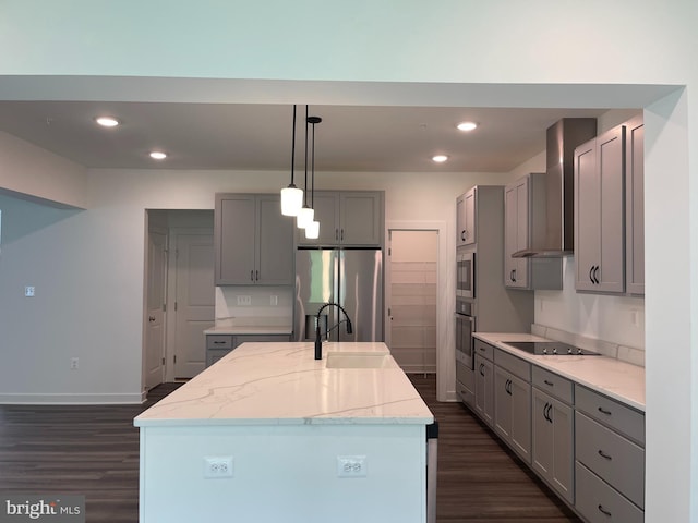 kitchen featuring gray cabinetry, a center island with sink, stainless steel appliances, wall chimney exhaust hood, and a sink