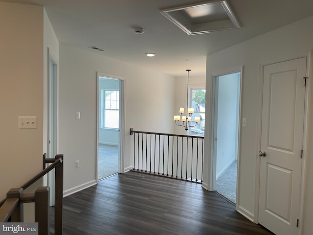 corridor featuring an upstairs landing, plenty of natural light, a chandelier, and dark wood-style flooring