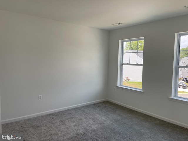 empty room featuring carpet, a healthy amount of sunlight, visible vents, and baseboards