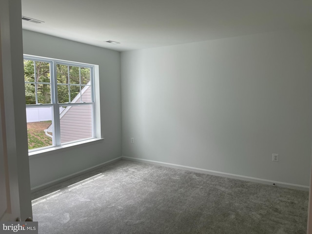 carpeted spare room featuring visible vents and baseboards