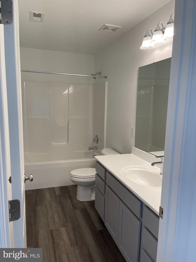 full bath featuring visible vents, toilet, bathing tub / shower combination, wood finished floors, and vanity