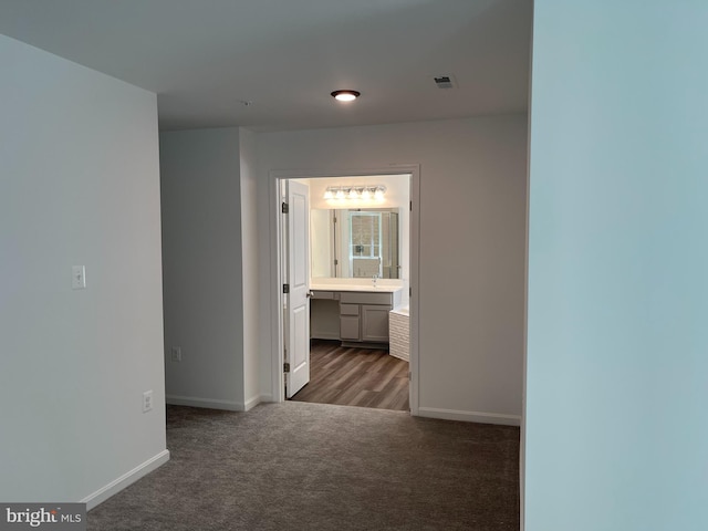 hall featuring carpet flooring, visible vents, and baseboards