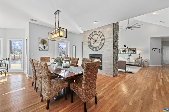 dining area with a ceiling fan, visible vents, lofted ceiling, light wood-style flooring, and a fireplace