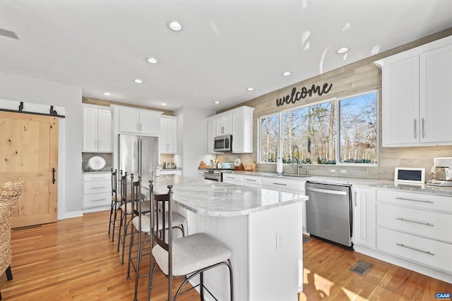 kitchen with premium appliances, light wood-style flooring, white cabinets, and a sink